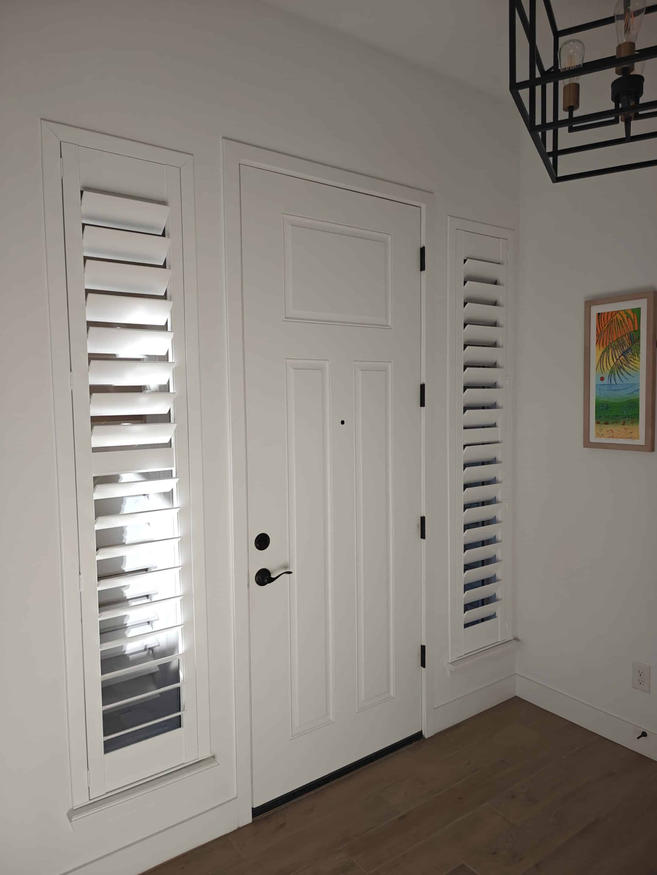 White composite shutters in two sidelights in a foyer.